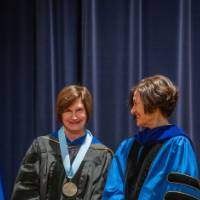 Provost Mili smiles at faculty member on stage